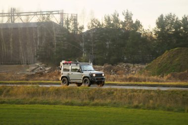 Gün batımında kırsal yolda giden SUV.