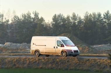 Açık yolda giden beyaz kargo minibüsü.