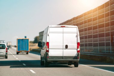 Önünde beyaz bir kargo kamyonu olan bir otoyol.