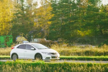 Beyaz şehir arabası inşaat alanının yakınında seyahat ediyor.