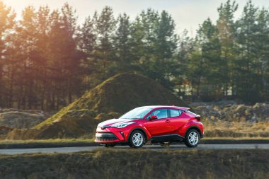 Yazın açık bir yolda kırmızı bir SUV sürüyordu.