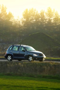 Güneşli bir kır yolunda giden SUV.