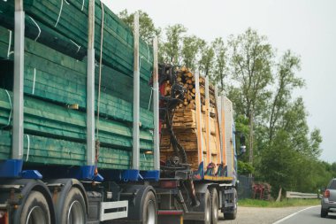 Taşıtlar kırsal yolda kereste ve kereste taşıyor.