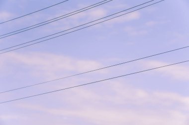 Açık mavi gökyüzü altında elektrik kabloları
