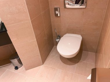 Duvara monte edilmiş tuvaleti ve kapalı kapağı olan özel bir banyo.