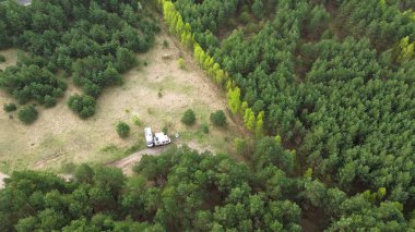 Yukarıdan yeşil çam ağaçları ve karavan.