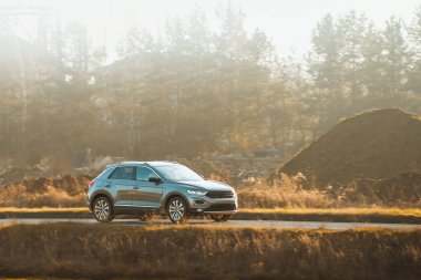 Güneşli bir kır yolunda giden SUV.