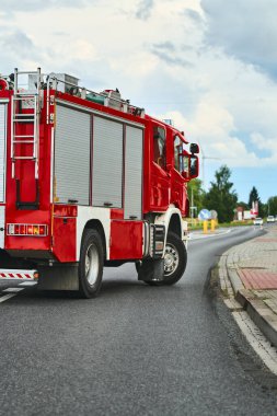 Banliyö mahallesinde kırmızı itfaiye aracı sürüyor.