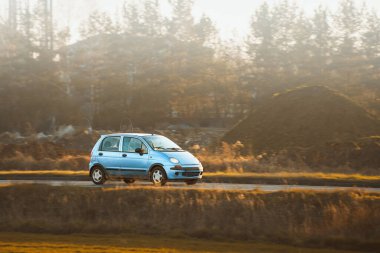 Kırsal yolda giden küçük bir hatchback arabası.