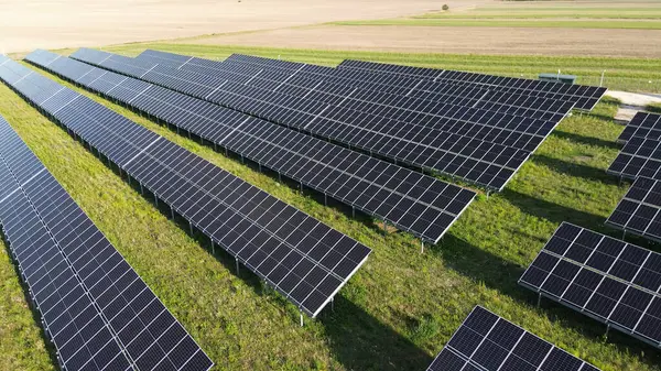 Güneş panelleri günbatımında sürdürülebilir enerji topluyor. Geniş bir güneş enerjisi santralinde temiz ve yenilenebilir enerji üretiyor.