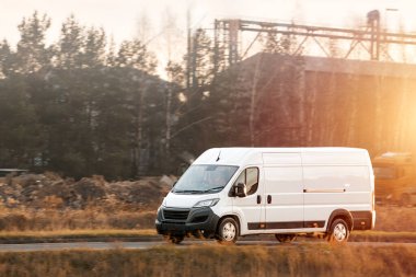 Manzaralı arka planı olan kargo aracı yolda.