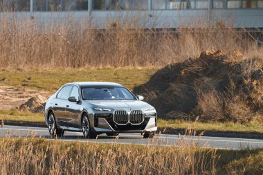 Elektrikli SUV boş köy yolunda ilerliyor.