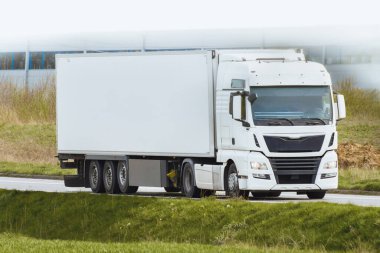 Kargo kamyonu gün ışığında otoyolda ilerliyor.