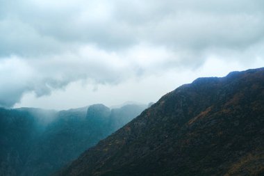 Bulutlu bir günde, bir dağ sırasının üzerinde sis akıyor.