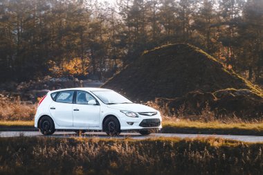 Siyah araba boş köy yolunda ilerliyor.