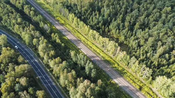 Ağaçlarla çevrili tren raylarının ve otobanın tepeden aşağı manzarası