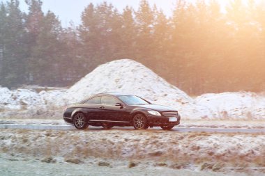 Kışın kar yağarken hareket eden zarif bir araba.