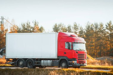 Kırsal alanda beyaz yük kamyonu sürüyor.