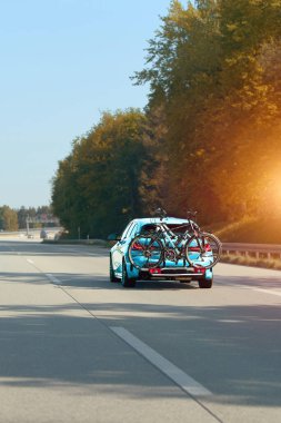 Bisikletli araba güneşli otoyolda ilerliyor.