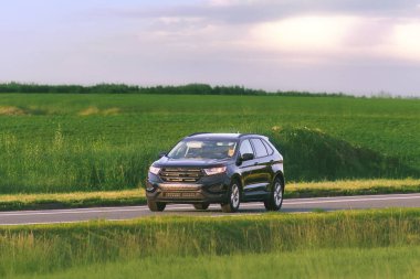 Sakin bir kırsal yolda modern bir SUV sürüyor.