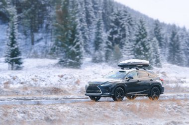 Kış dağlarında karlı patikada gezinen SUV