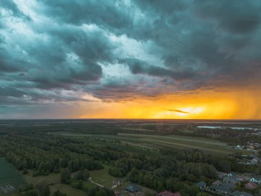 Kırsal alan, gün batımında dramatik fırtına bulutlarıyla