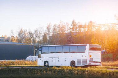 Gün batımında yolda beyaz otobüs