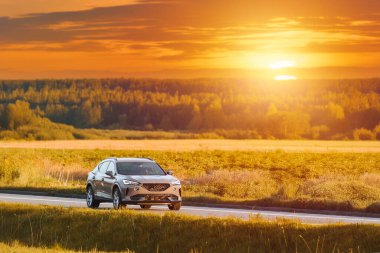 Güzel bir gün batımında manzaralı bir yolda lüks bir SUV.
