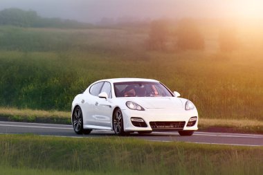 Yeşil tarlalardan geçen parlak yönetici arabası.