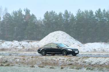 Islak kış yolunda giden lüks bir araba.
