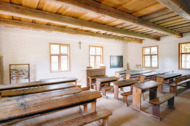 Ahşap masaları ve bankları olan antika bir sınıf.