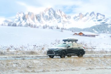 Kış manzarasında çatıda kargo taşıyan bir araba.