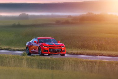 Yeşil kırlarda kaslı bir araba sürüyordu.