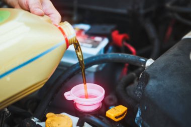 Tamirci araba motoruna sentetik yağ ekliyor