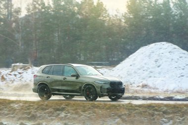 Beyaz bir SUV kış ormanından geçiyor.