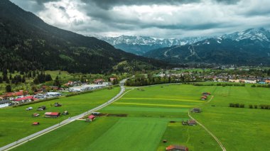 Bahar mevsiminde köy manzarasına hükmeden nefes kesici Bavyera Alpleri