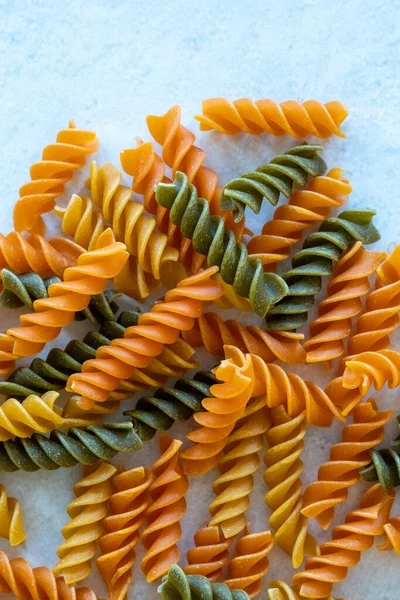 stock image Dry tricolor fusilli pasta on white granite background.