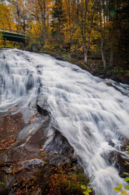 Kuzeydoğu Vermont 'ta çağlayan şelale ve ilerideki otoyol üst geçidi ile yapraklar dökülüyor..