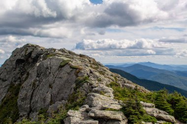 Bare rock and distant mountains on Vermont hill top with dramatic clouds.