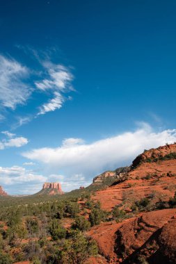 Uzak bulutlar Sedona, Arizona 'daki kızıl kaya ve kayalıkları canlandırıyor.