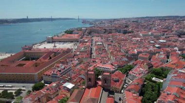 Lizbon 'un kırmızı çatılarının üzerinde 25 Nisan köprüsü ve Tagus Nehri' nin arka planında