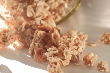 Granola sıcak güneş ışığında cam kavanozdan dökülür.