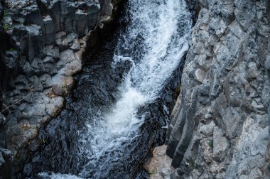 Mountain stream Meshushim. Nahal Meshushim. Rocks in the form of hexagonal basalt columns. Golan Heights. Israel.