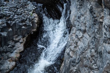 Mountain stream Meshushim. Nahal Meshushim. Rocks in the form of hexagonal basalt columns. Golan Heights. Israel.