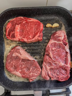 Kızartma tavasında kızartılmış üç tane pembe mermer biftek. Yüksek kalite fotoğraf