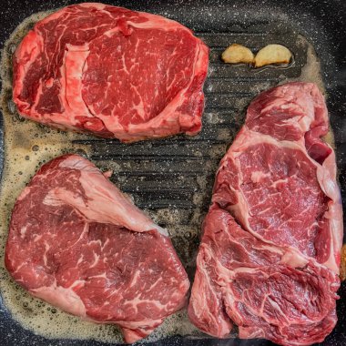 Kızartma tavasında kızartılmış üç tane pembe mermer biftek. Yüksek kalite fotoğraf