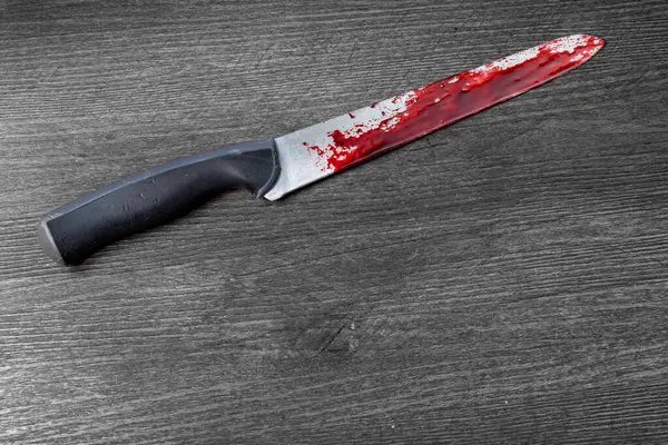 Tahta bir yüzeyde kanlı bir bıçak yatıyor. Yüksek kalite fotoğraf
