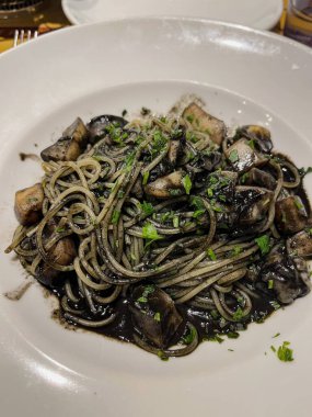 Lokantada servis edilen beyaz tabakta siyah mürekkep balığı spagettisi. Yüksek kalite fotoğraf