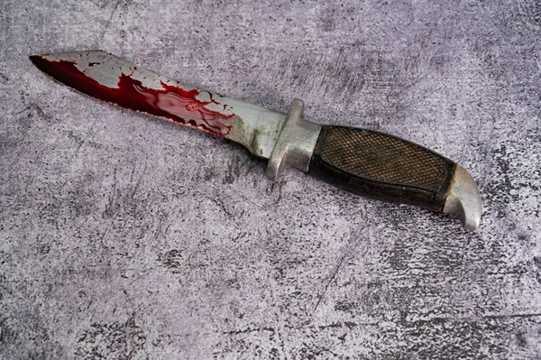 Kana bulanmış bir savaş bıçağı mermer bir yüzeyde bulunur. Yüksek kalite fotoğraf