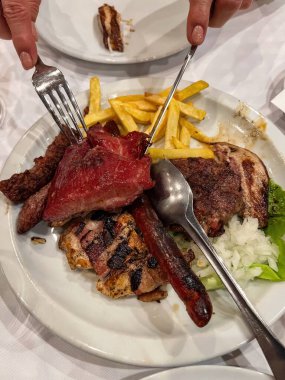 Patates kızartması ve salatayla servis edilen bir tabakta sosis ve birkaç çeşit ızgara et. Yüksek kalite fotoğraf